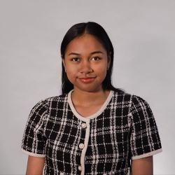 A person with long heair wearing a plaid top pses for a photo